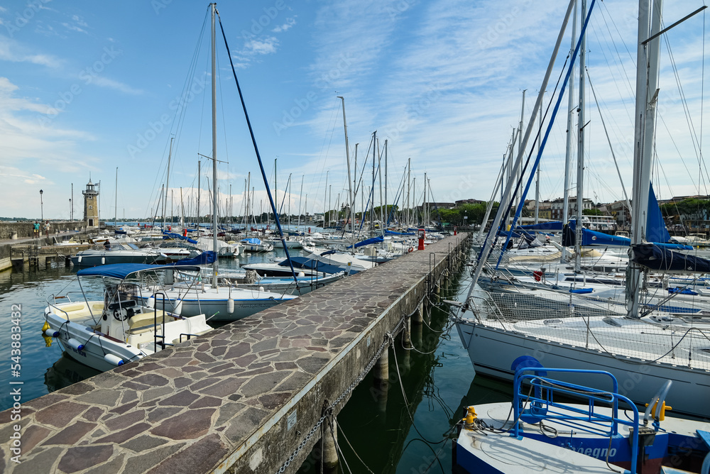 Fototapeta premium sailing boats and speedboats are moored in the port of Lake Garda Italy