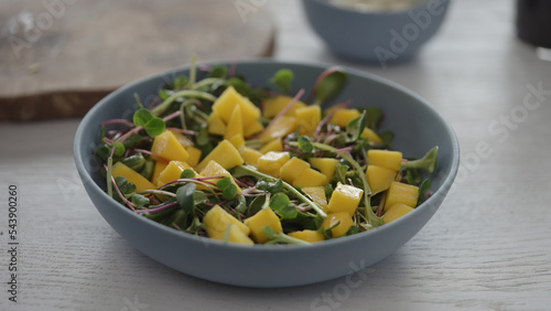 salad with mango and micro greens in blue bowl