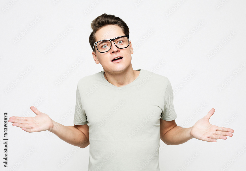 Shocked amazed surprised man wear eyeglasses standing keeping mouth open spreading hands over white background Shocked amazed surprised man wear eyeglasses standing keeping mouth open spreading hands over white background