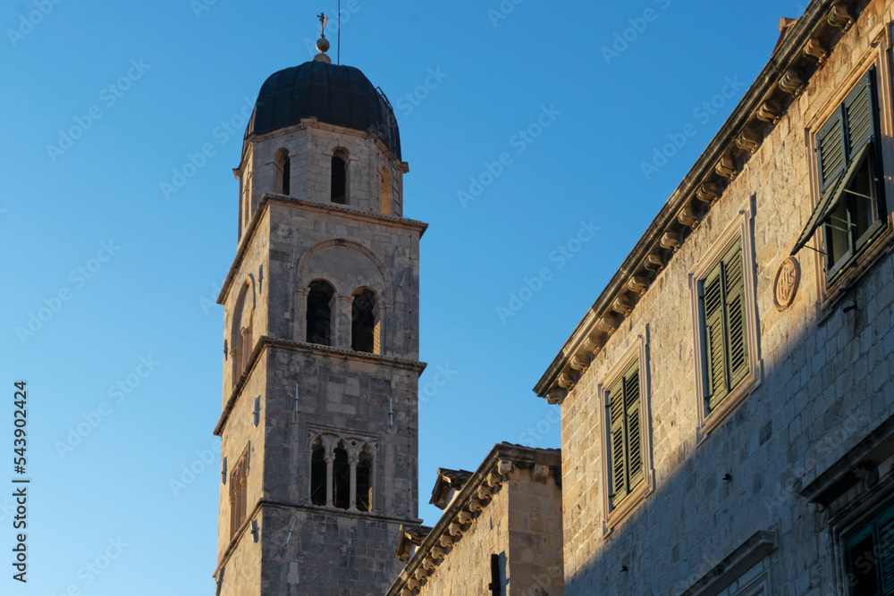 Fototapeta premium Detail of church and bell tower of the Franciscan church in clear sunny day at sunset in Dubrovnik, Croatia. Religious or travel or architecture background. 