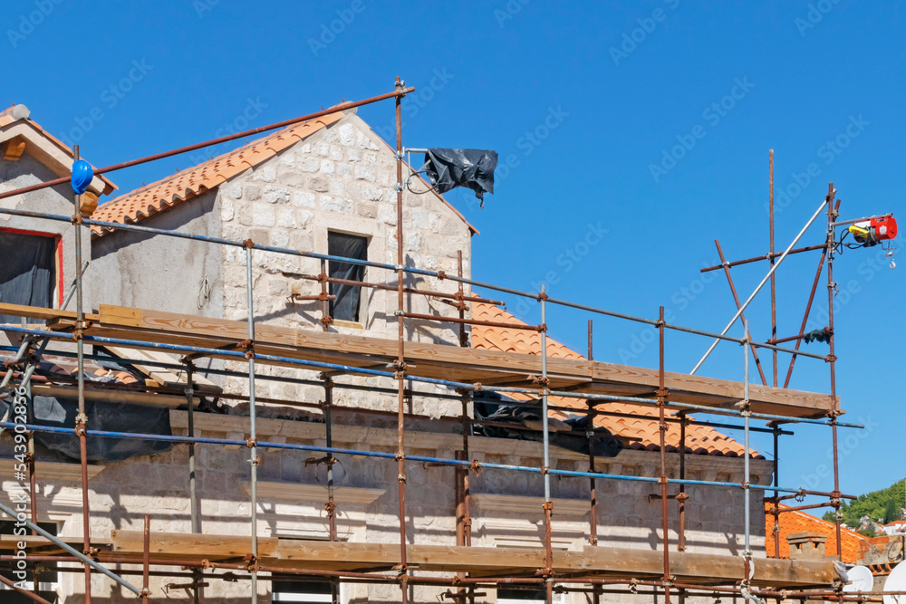 Obraz premium Detail of exterior construction and renovation works in Dubrovnik Croatia using simple scaffolding and hoisting tools. Construction background illustrating traditional methods of work.