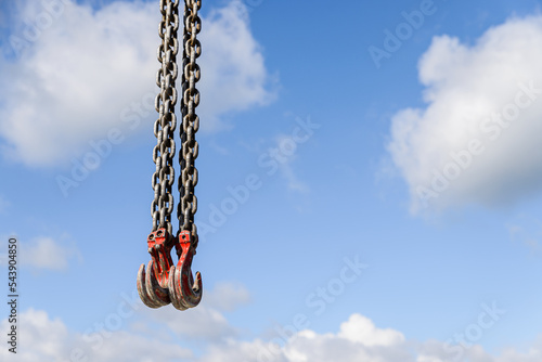 Lifting production equipment. Crane metal hooks on blue sky background, copy space.