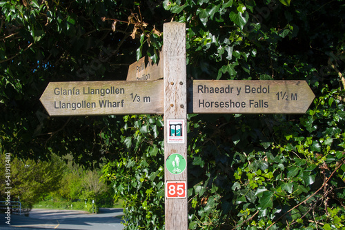 Wooden sign showing the direction and distance to the Llangollen Wharf and the Horseshoe Falls in Llangollen, Wales, UK.