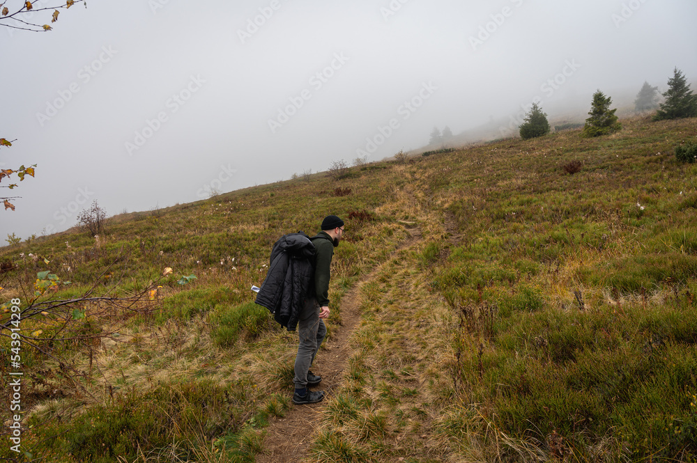 A man with a backpack on his back walks along the path, the top of the mountain, fog, cloudy. Recreation. Selective focus, nature A man with a backpack on his back walks along the path, the top of the mountain, fog, cloudy. Recreation. Selective focus, nature
