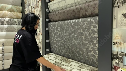 Brunette woman in the store makes a purchase of wallpaper photo