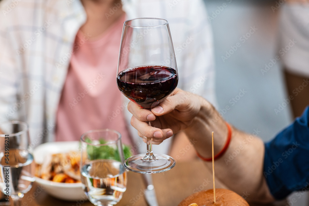 Obraz premium leisure, drinks and people concept - close up of man with glass drinking red wine at restaurant