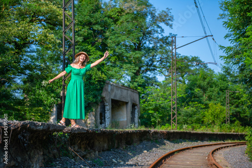 a woman in a green dress waves her hand on the railway