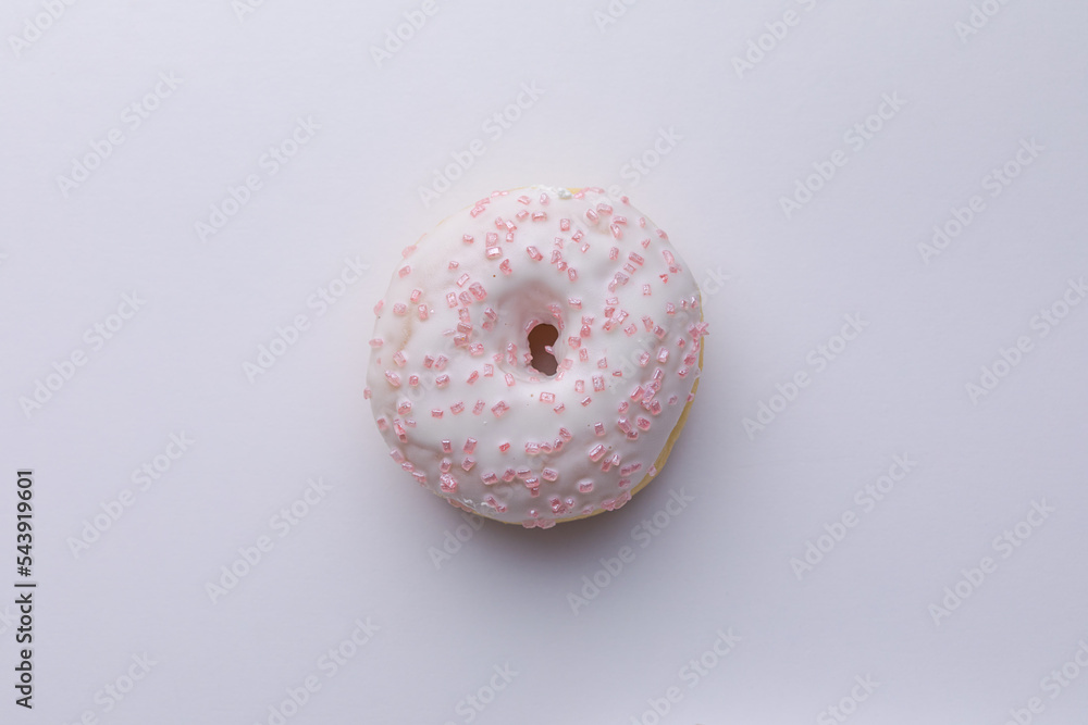 Ciambella con glassa e zuccherini rosa su superficie bianca Ciambella con glassa e zuccherini rosa su superficie bianca