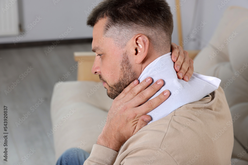 Man using heating pad on sofa at home Man using heating pad on sofa at home