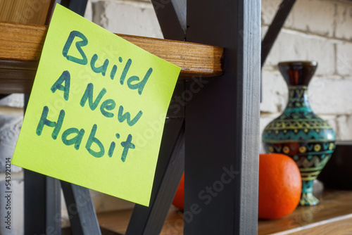 Sticker with inscription Build a new habit on the shelf. photo