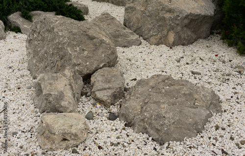 Large gray stones lie on small white pebbles and sand. Sochi, Adler.