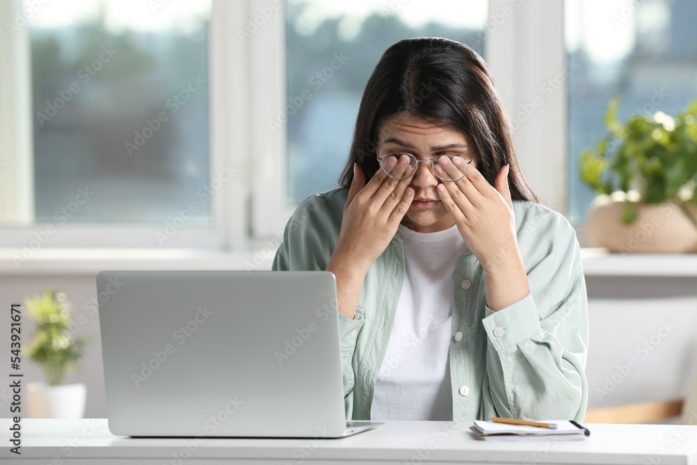 Young woman suffering from eyestrain at desk in office Young woman suffering from eyestrain at desk in office