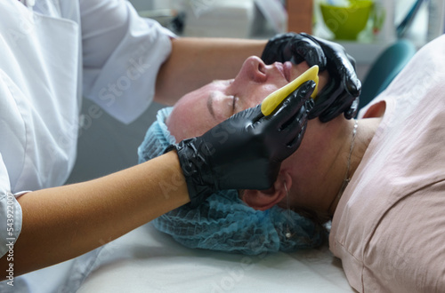 A woman is given a facial massage using a massage tile. Close-up.