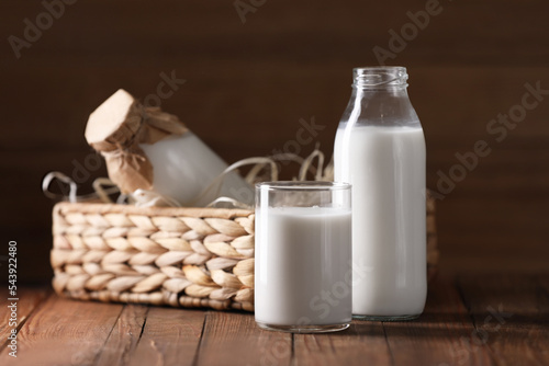 Tasty fresh milk in bottles and glass on wooden table