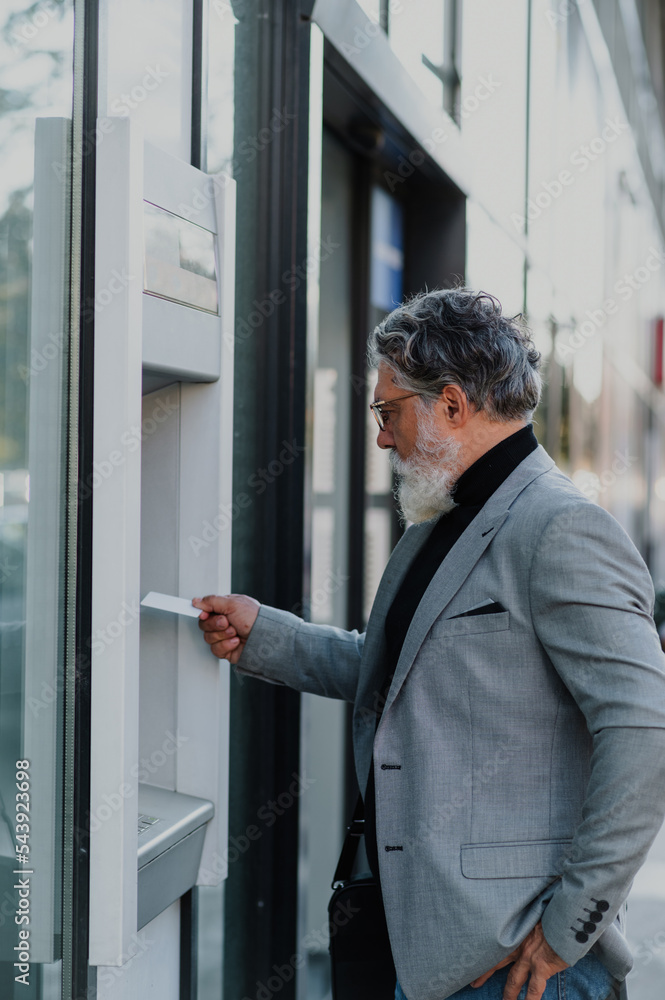 Senior business man using atm machine and credit or debit card Senior business man using atm machine and credit or debit card