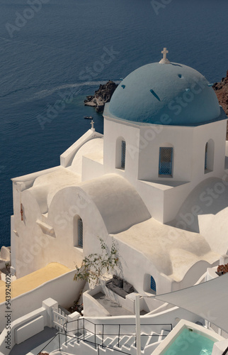 Oia, Santorini, Greece. 2022. Blue domed church with cross with a backdrop of the Aegean Sea,