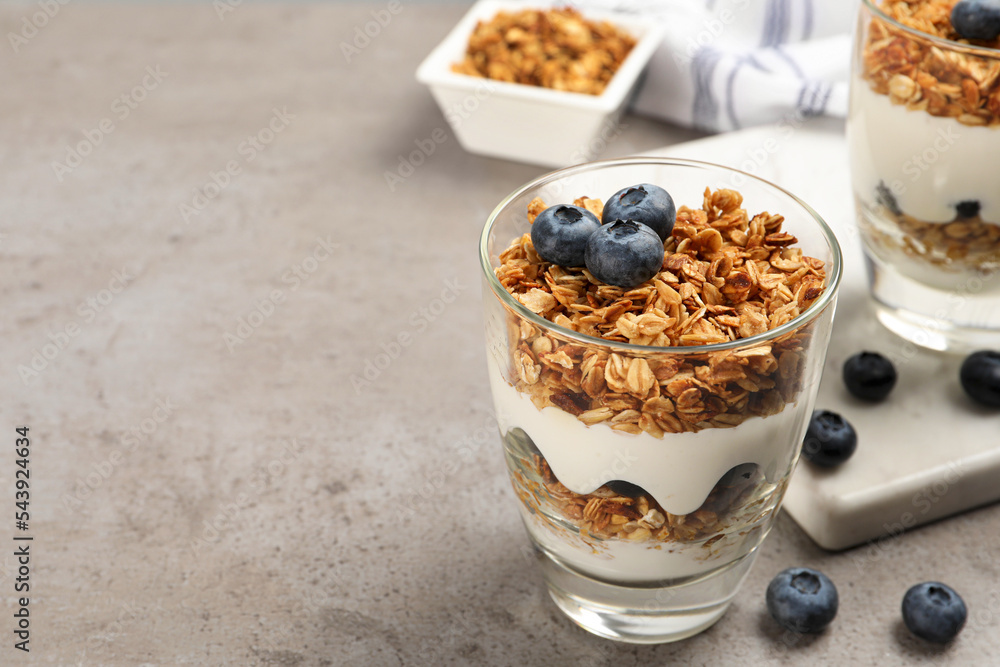 Glasses of yogurt with granola and blueberries on grey table, closeup. Space for text Glasses of yogurt with granola and blueberries on grey table, closeup. Space for text