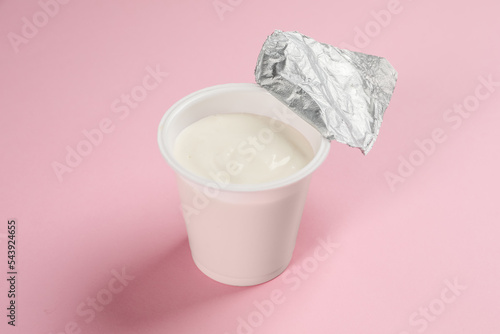 Plastic cup with tasty yogurt on pink background