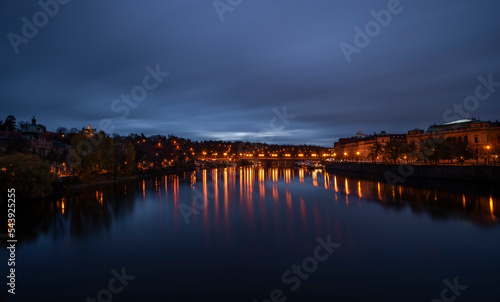 Dark capital Prague before cloudy color sunrise over Vltava river photo