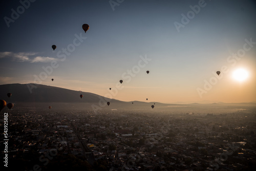 A group of hot air balloons over flying in mexico during sunrise