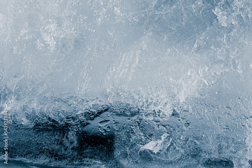 Ice texture background. The textured cold frosty surface of crushed ice block on dark blue background.