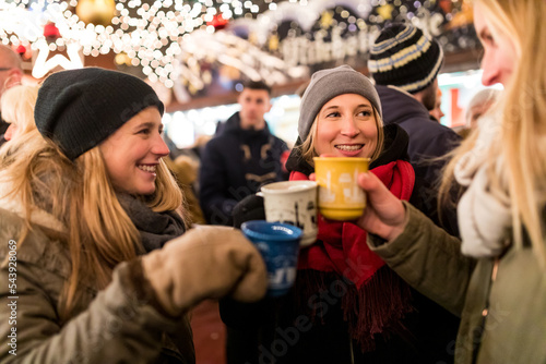 Happy young women with cups of mulled wine at Christmas market in Innsbruck