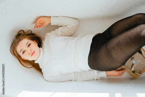 seductive girl in pantyhose lies in a white empty bathroom, looks at the camera photo