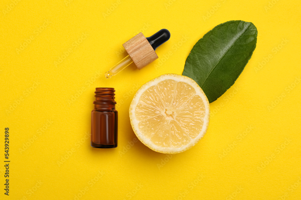 Bottle of citrus essential oil, pipette and fresh lemon on yellow background, flat lay Bottle of citrus essential oil, pipette and fresh lemon on yellow background, flat lay