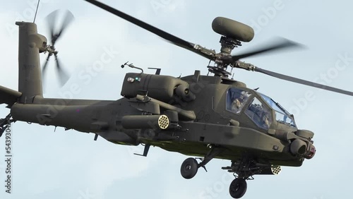 detailed close-up of ZM707 British army Boeing Apache AH2 Attack helicopter gunship (AH-64E AH64E) flying low across the frame, left to right, salute from gunner, Wilts UK