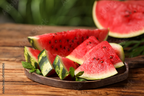 Slices of delicious ripe watermelon on wooden table outdoors