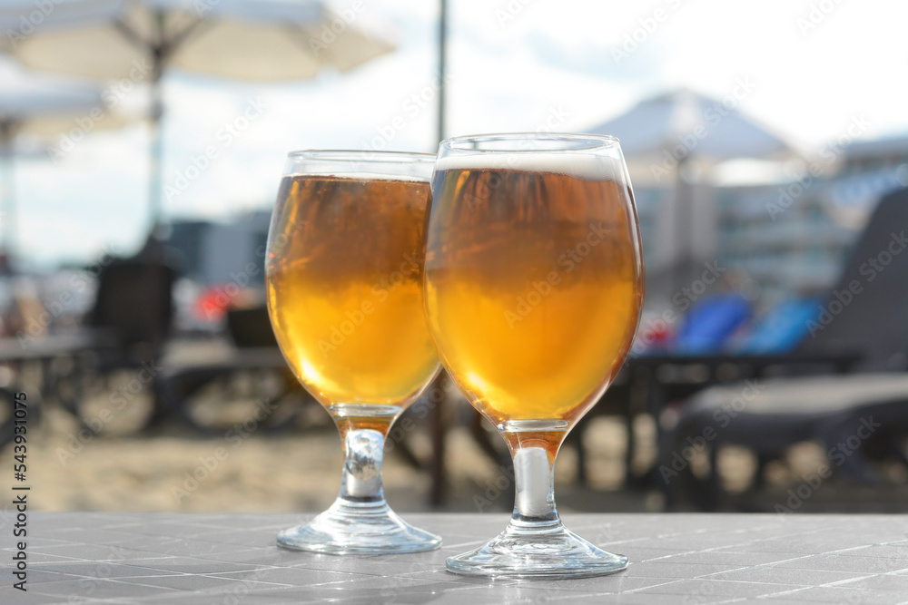 Cold beer in glass on beach, closeup Cold beer in glass on beach, closeup
