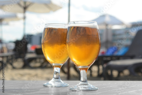 Cold beer in glass on beach, closeup