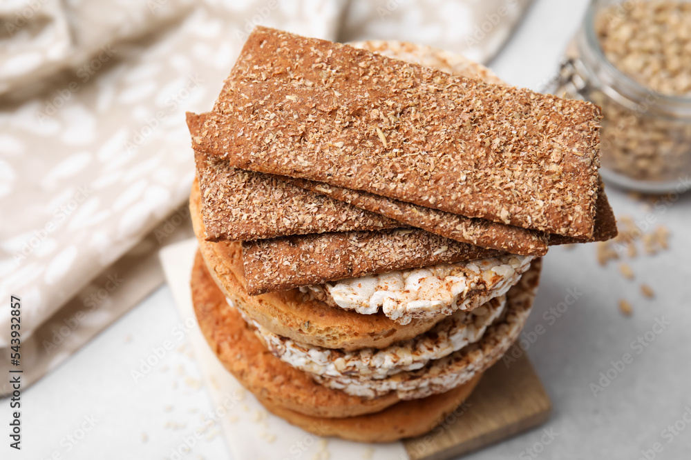 Stack of rye crispbreads, rice cakes and rusks on white table, closeup