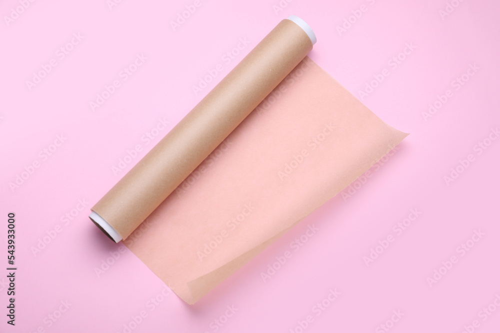 Roll of baking paper on pink background, top view