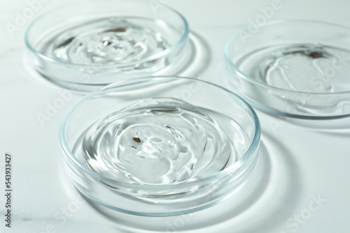 Petri dishes with liquids on white marble table, closeup