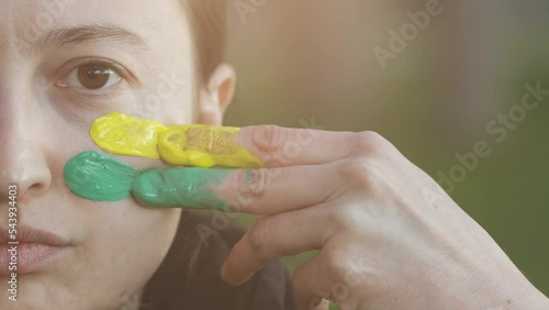 Supporter Painting Face and Looking at Camera. Football Fan Preparing for the Match. Colored Face with Flag Colors Yellow and Green. Slow Motion 4K Prores 422 photo