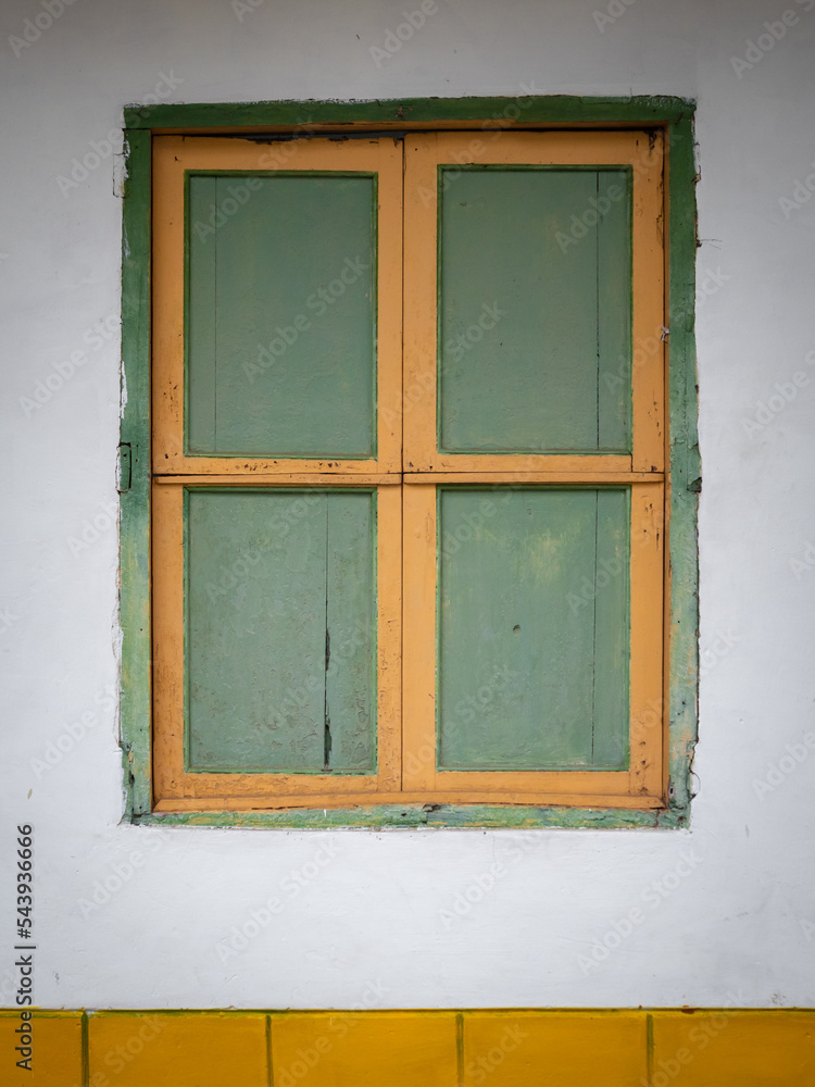 Fototapeta premium Green and Yellow Window and a White Background, Characteristic of the Town of Jerico, Antioquia, Colombia