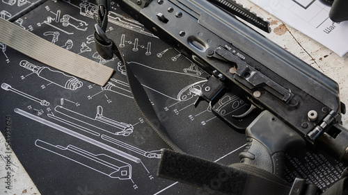 Картината върху платно Trigger of a Kalashnikov assault rifle with a background depicting the dismantli