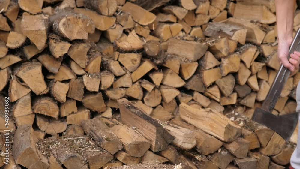 Closeup of mans hands with a log and a sharp vintage axe chop wood for fire heat. Detail of axe, wood chips fly around. Preparation logs for cold wintertime. Alternative fuel. Energy crisis in Europe. Closeup of mans hands with a log and a sharp vintage axe chop wood for fire heat. Detail of axe, wood chips fly around. Preparation logs for cold wintertime. Alternative fuel. Energy crisis in Europe.