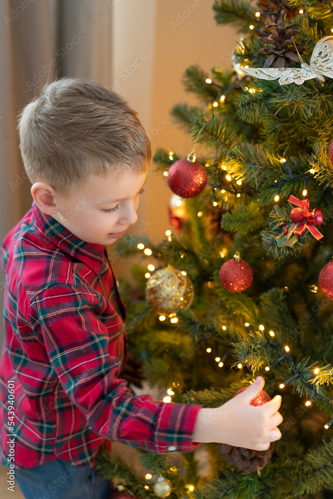 Little boy is decorating the Christmas tree