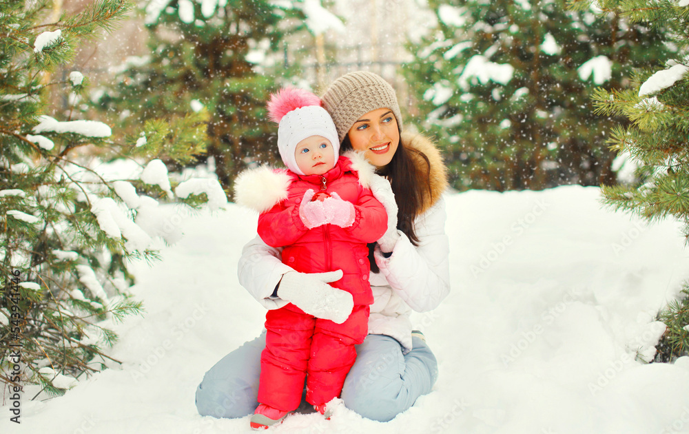 Winter portrait of happy smiling mother and little girl child outdoors on christmas tree background with snowflakes Winter portrait of happy smiling mother and little girl child outdoors on christmas tree background with snowflakes