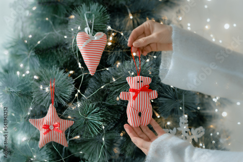 A woman's hand decorates the Christmas tree with fabric toys