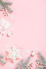 Christmas decorations at pink background. Fir tree, present box and white christmas decorations. Top view with copy space.