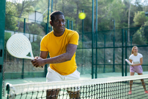 Portrait of a african american man engaged in a popular sport padel with a racket outdoor court