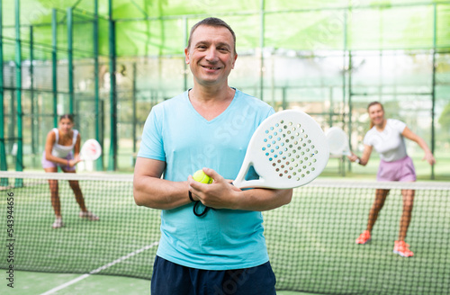 Portrait of cheerful man padel tennis player in outdoor court. © JackF