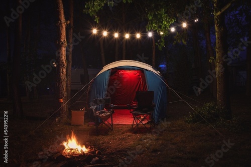 Atmospheric night adventure. Tent with a midnight fire in the forest.