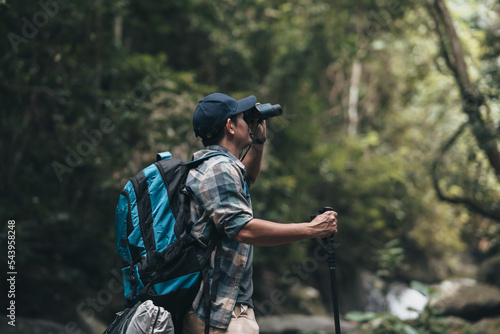 Hikers use binocular to see animals and view landscape with backpacks in the forest. hiking and adventure concept.