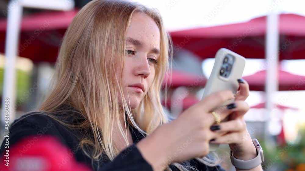 Portrait of a blonde-haired woman typing a message on her smartphone. Focused, caucasian girl in her 20s using wireless network while surfing internet. High quality 4k footage Portrait of a blonde-haired woman typing a message on her smartphone. Focused, caucasian girl in her 20s using wireless network while surfing internet. High quality 4k footage