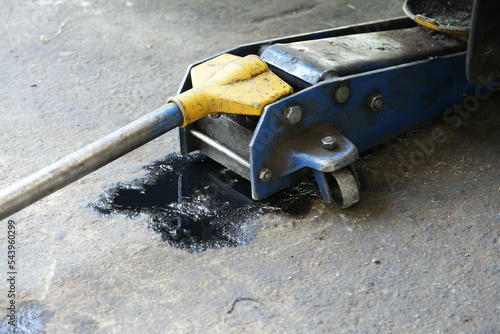 Black engine oil smeared on the floor under the jack.