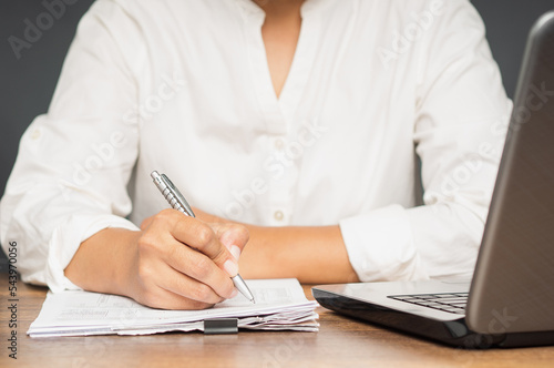Businesswoman in a white shirt signing a lease contract or agreement while sitting in the office